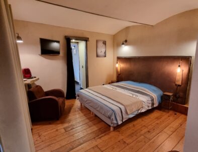 Décor cosy de la chambre d'hôtes Jabron au rez-de-chaussée avec un plancher bois et un plafond vouté. Deux fauteuils de velours marron vous attendent pour un moment de détente.