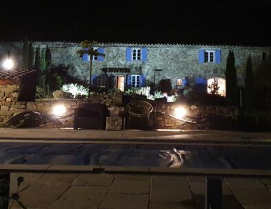 Vue nocturne depuis la piscine avec des éclairages illuminant la façade arrière